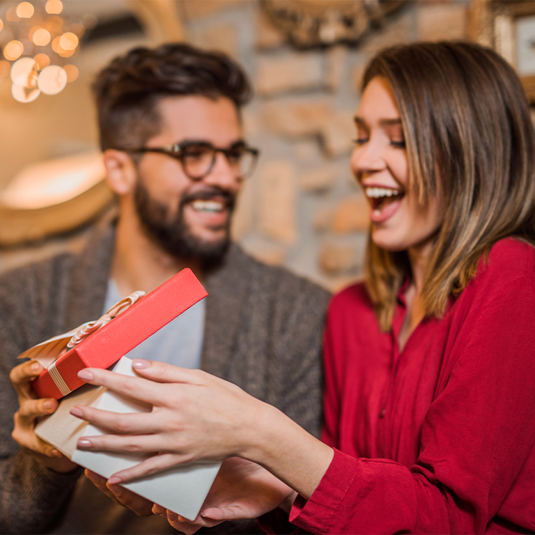 Cheerful young woman receiving gift from her boyfriend 