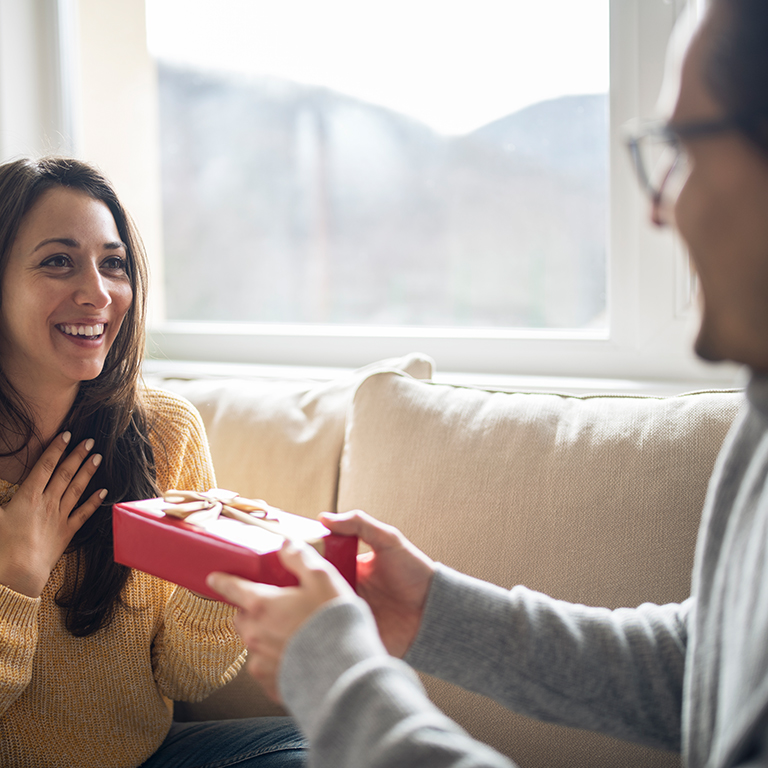 Cheerful young woman receiving gift from her boyfriend 